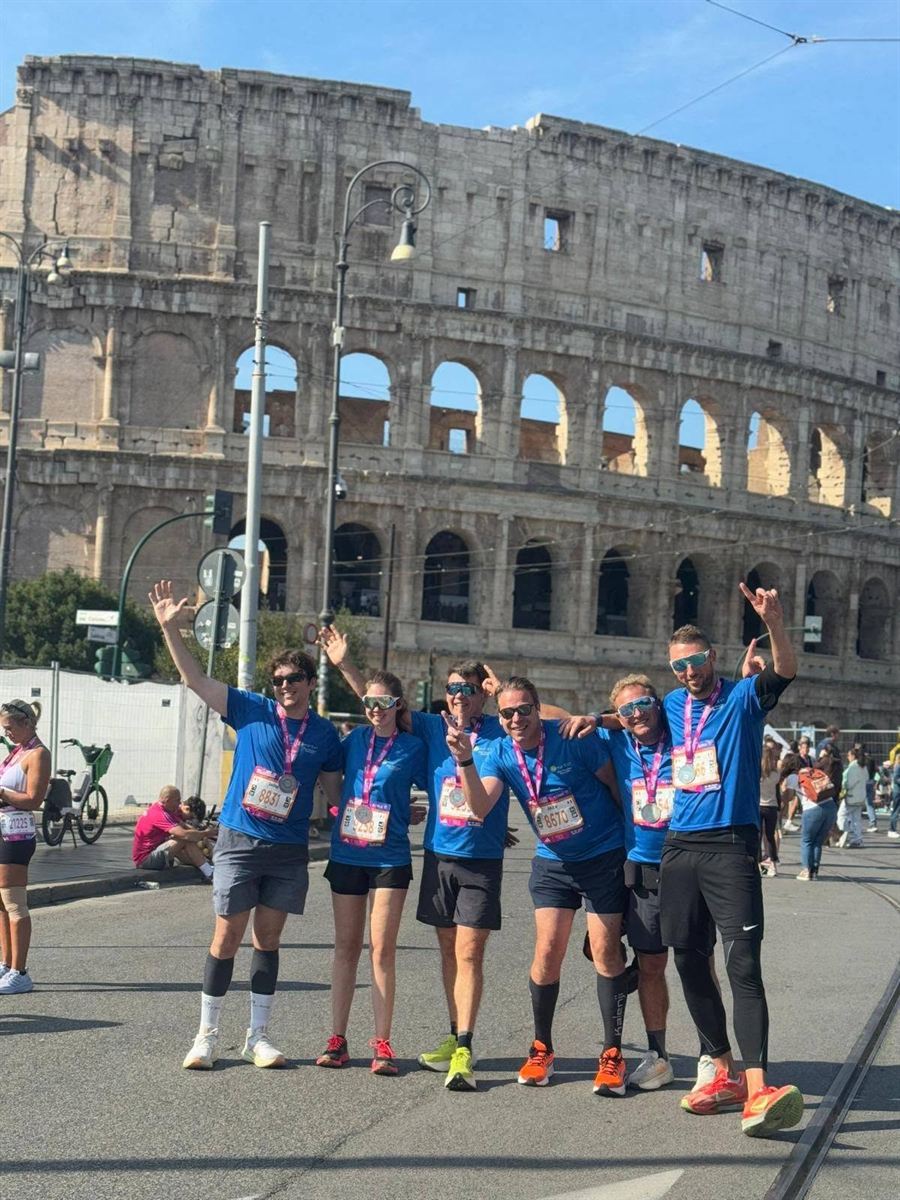 Groupe de coureurs en maillots personnalisés, médaille au cou, devant le Colisée à Rome